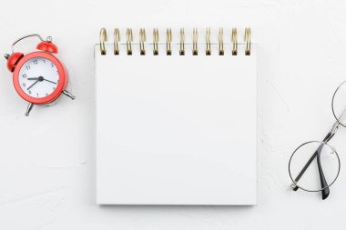 Beyaz dokulu masada kırmızı alarmlı beyaz spiral dizüstü bilgisayar. Düz yatıyordu mockup.