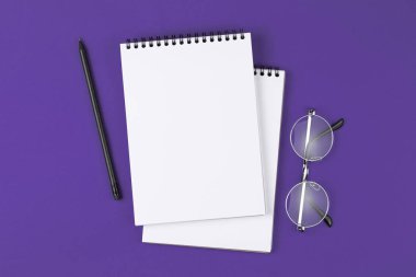 mor arka plan üzerinde kalem ve gözlük ile açık defter