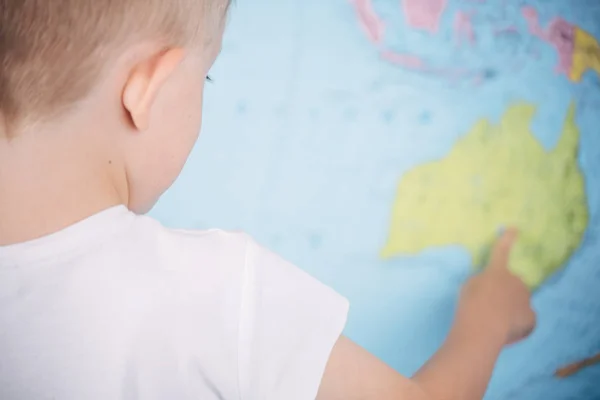 世界地図の背景にいる小さな男の子は — ストック写真