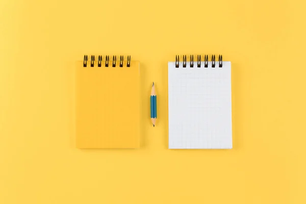 Notizblock mit Bleistift auf gelbem Hintergrund flach gelegt. — Stockfoto