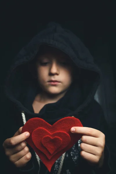 Ребенок с красным сердцем на темном фоне — стоковое фото