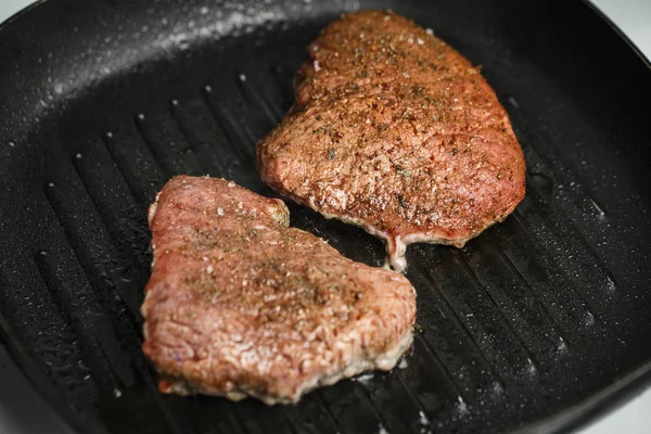 A carne crua em uma panela frita-se em casa com temperos — Fotografia de Stock