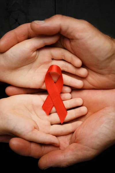 AID red ribbon in hand on a black wooden background