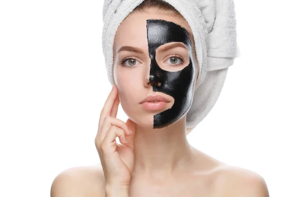 Chica con máscara cosmética negro en la cara y la cabeza envuelta en toalla — Foto de Stock