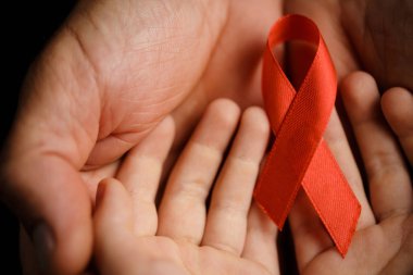 Koyu arkaplanda AID kırmızı kurdelesi olan çocuk