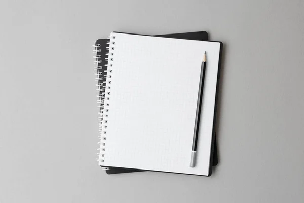 Vista superior de um caderno preto aberto com lápis em um fundo cinza — Fotografia de Stock