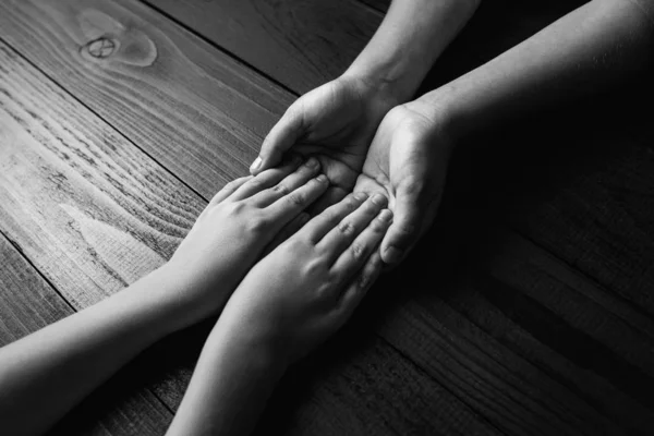 Τα χέρια τεντώνεται και συγκρατεί το ένα το άλλο σε μαύρο ξύλινο φόντο. μαύρο και άσπρο. — Φωτογραφία Αρχείου