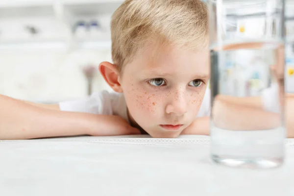 Kleine jongen in de keuken met een glas schoon water — Stockfoto