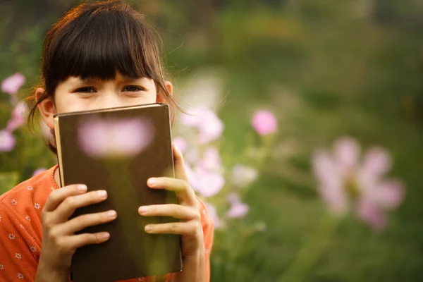 Cute girl is reading outdoors on an sunny day, international literacy day.