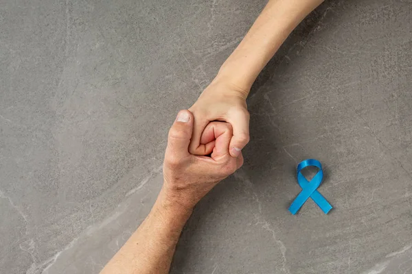 Hands holding prostate cancer blue ribbon — Stock Photo, Image