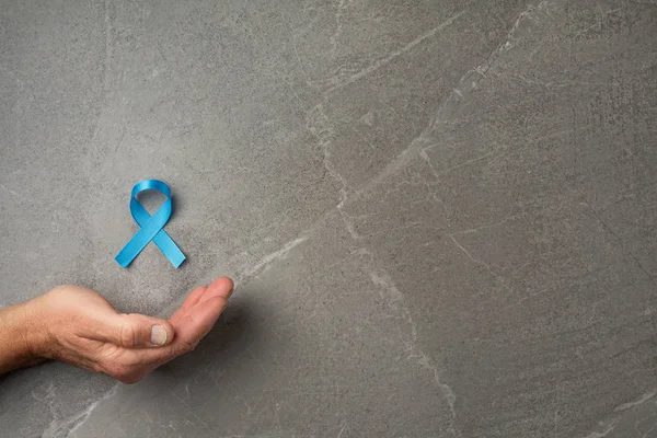 hands holding prostate cancer blue ribbon