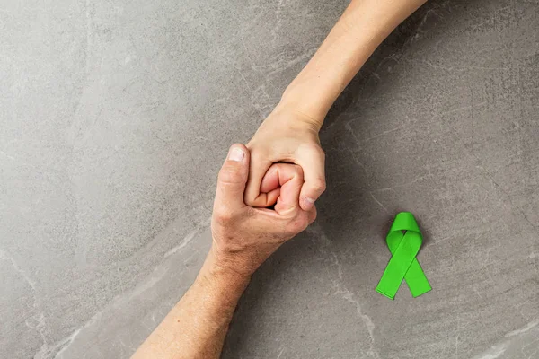 Stock image hands holding green ribbon, Lymphoma Cancer