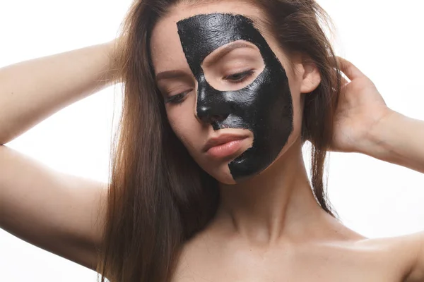 Meisje met zwart cosmetisch masker op gezicht — Stockfoto