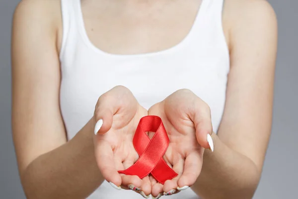 Mani femminili con il nastro rosso di sensibilizzazione all'AIDS — Foto Stock