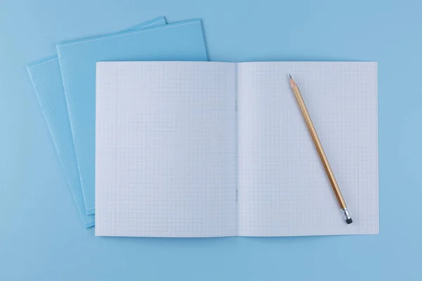 Zeszyt szkolny z ołówkiem na niebieskim stole — Zdjęcie stockowe