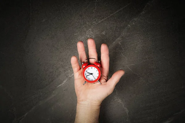 Relógio de alarme vermelho nas mãos vista superior — Fotografia de Stock