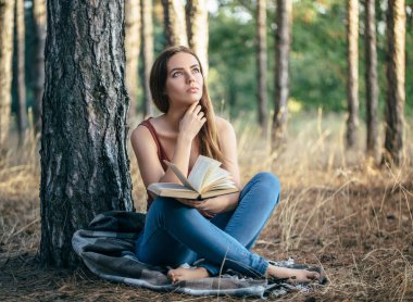 Kız elinde kitapla ağaç altında rüya görüyor.