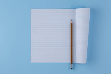 Okul defterinde mavi bir masa üzerinde kalem var.