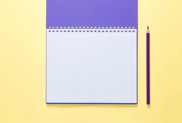 Cuaderno abierto con lápiz sobre fondo amarillo — Foto de Stock