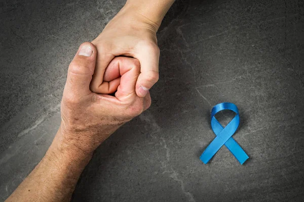 hands holding prostate cancer blue ribbon