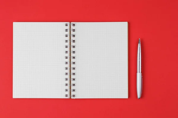 Notebook with pen on red background — Stockfoto