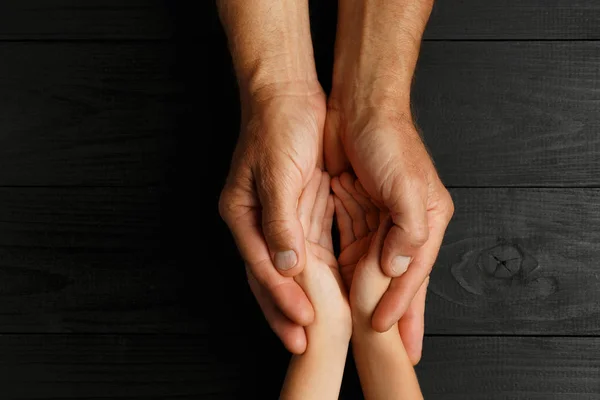 Çocuğun elini tutan yaşlı bir adamın elleri.