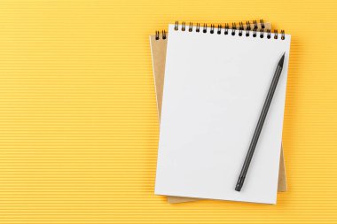 Sarı arkaplanda kurşun kalemle birlikte defteri aç