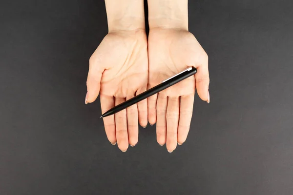 Fekete toll a kezében fekete háttér, felső nézet. — Stock Fotó
