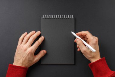 Elinde siyah kalem olan defter.