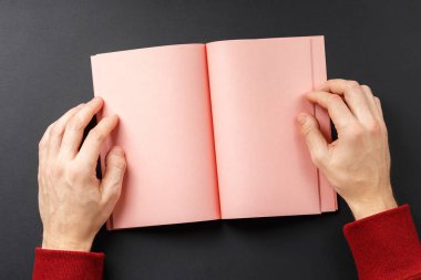 Siyah arkaplanda elleri olan defteri aç