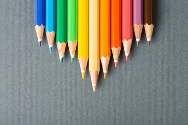 Renkli kalemler gri arkaplanda sıraya dizildi