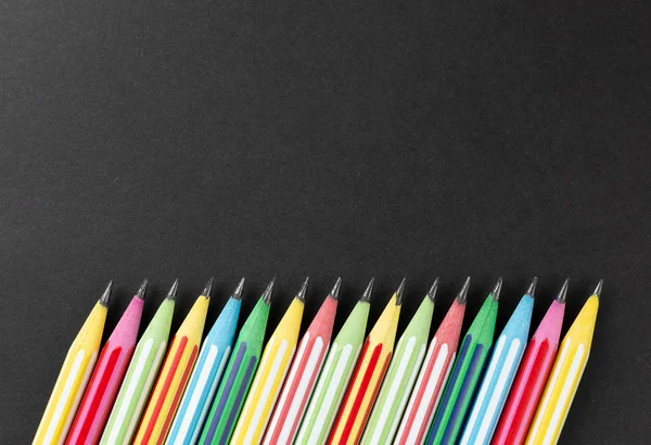 Colored pencils in row on a black background — Stock Photo, Image