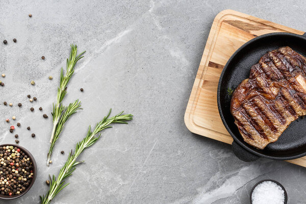 fried steak in pan on gray marble table top view