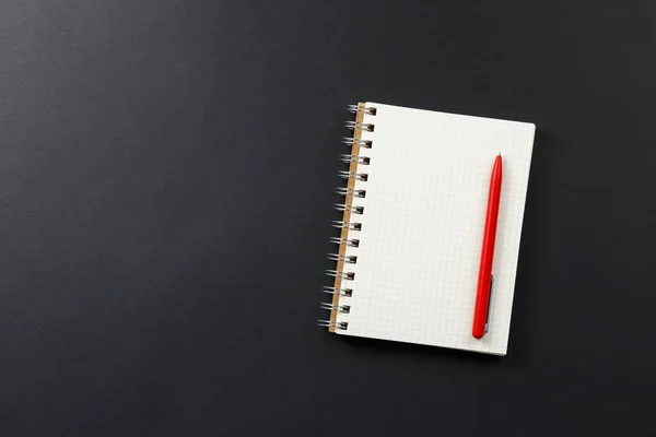 Cuaderno con pluma roja sobre fondo negro — Foto de Stock