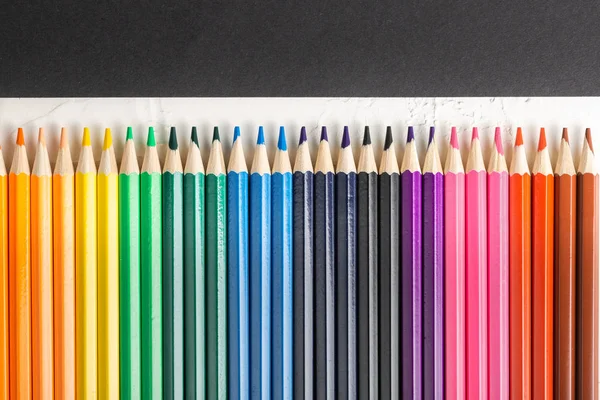Colored pencils in row on a black background — Stock Photo, Image