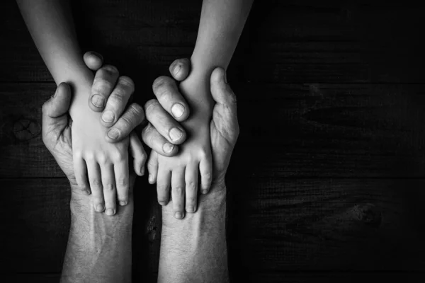 Mãos adultas segurando as mãos da criança, preto e branco . — Fotografia de Stock