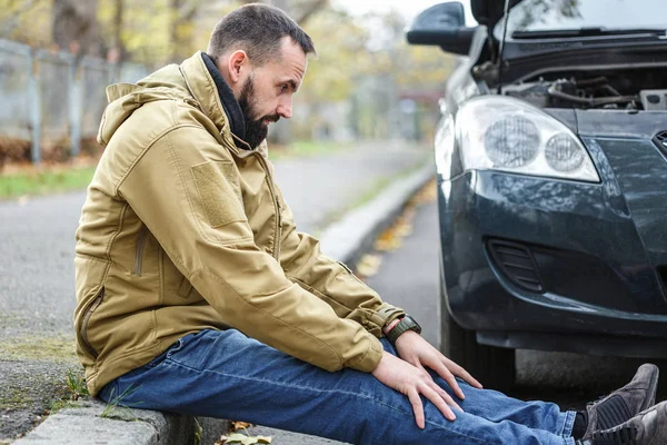 Guy is repairing car on the road