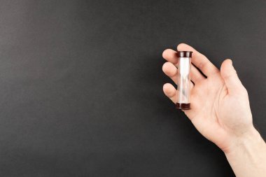 Siyah arka planda avuç içlerindeki kum camları.