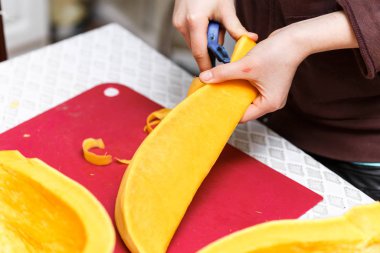 Eller turuncu balkabağındaki sebzeleri soyarlar.