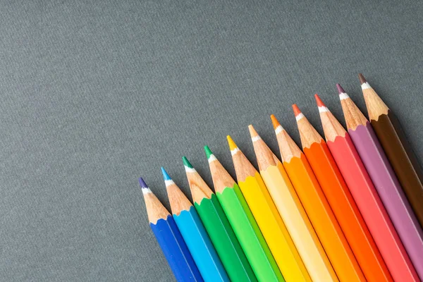 Colored pencils in row on a gray background — Stock Photo, Image
