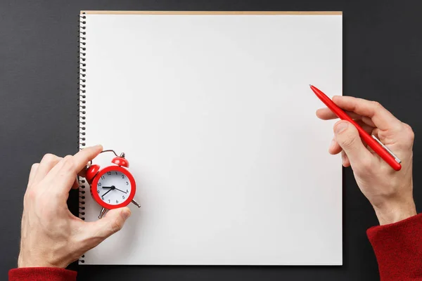 Notebook com despertador vermelho nas mãos — Fotografia de Stock