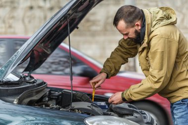 Adam yolda araba tamir ediyor.