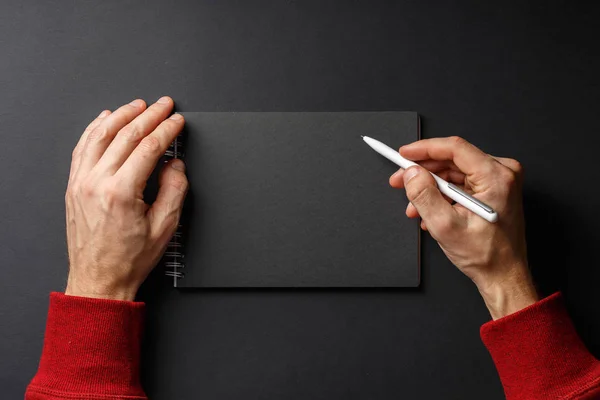 Notebook com caneta preta nas mãos em preto — Fotografia de Stock