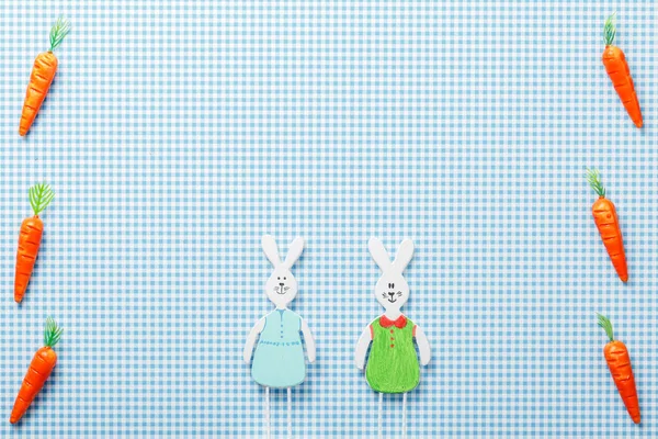 two rabbits and carrots lying on blue background