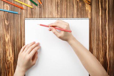 Ahşap masaya renkli kalemler ve not defterleri.