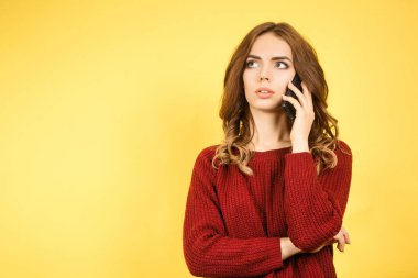 Kırmızı kazaklı kadın telefonda konuşuyor.