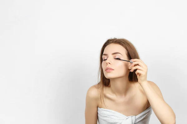 Mooie vrouw in een handdoek maken make-up — Stockfoto