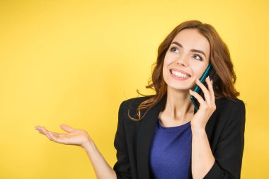 Kadın cep telefonuyla konuşuyor, sarı arka plan. 