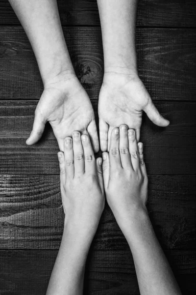 Руки розтягуються і тримаються один з одним на чорному — стокове фото