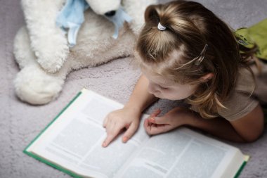 Güzel küçük kız en sevdiği oyuncağı okuyor.